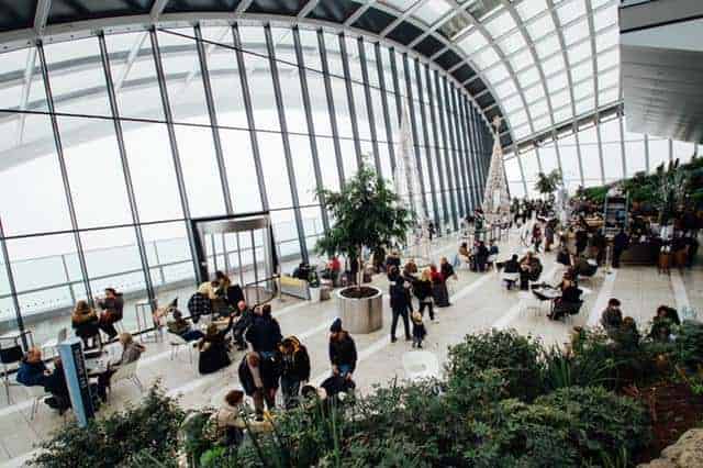 Crowd of people in glass building surrounded by plants