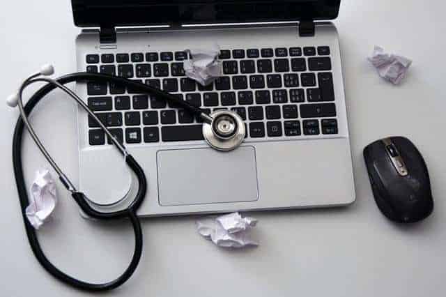 Laptop covered in scrap paper and stethoscope a part of (Medical Leadership Careers Coaching)