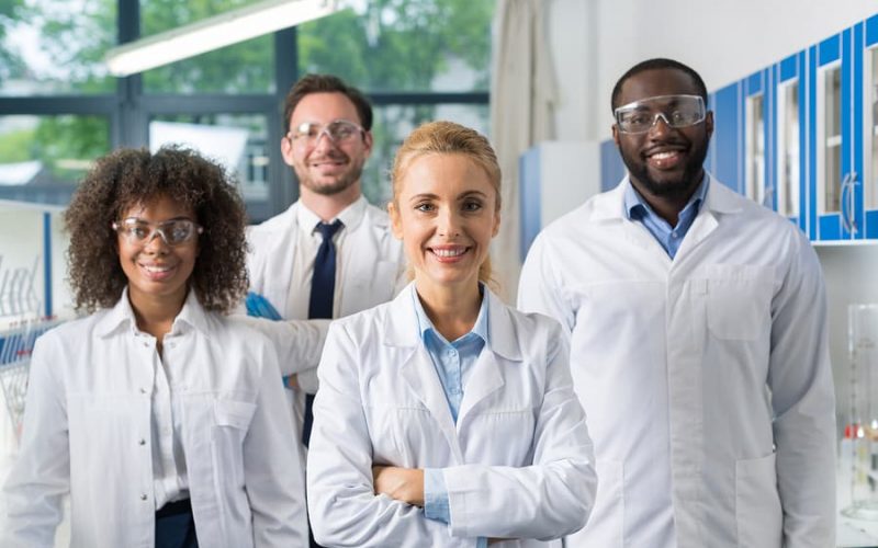 Smiling Group Of Scientists In Modern Laboratory With Female Leader