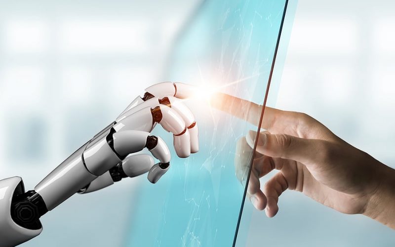 Robot hand touching human hand through glass pane