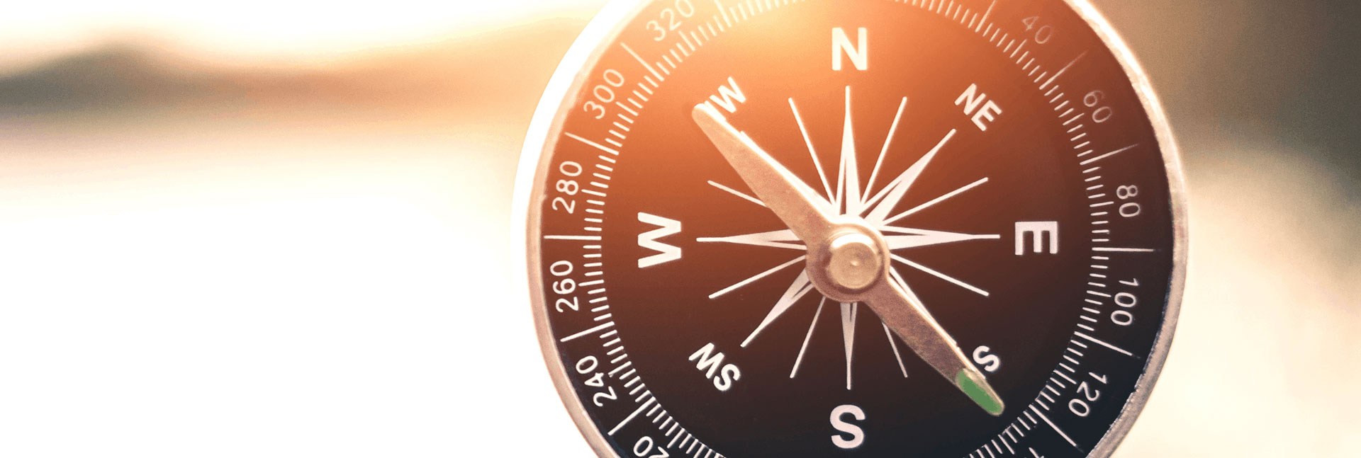 Compass with blurred sunset in background